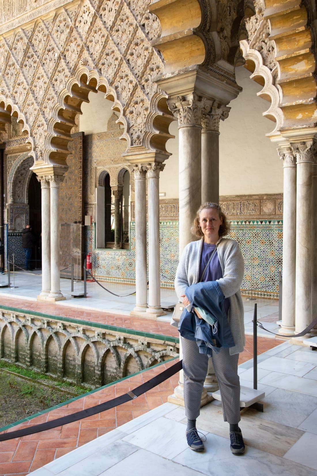 Anne in the Patio de las Doncellas at the Real Alcázar of Seville, with Moorish horseshoe arches and intricate tilework framing the courtyard